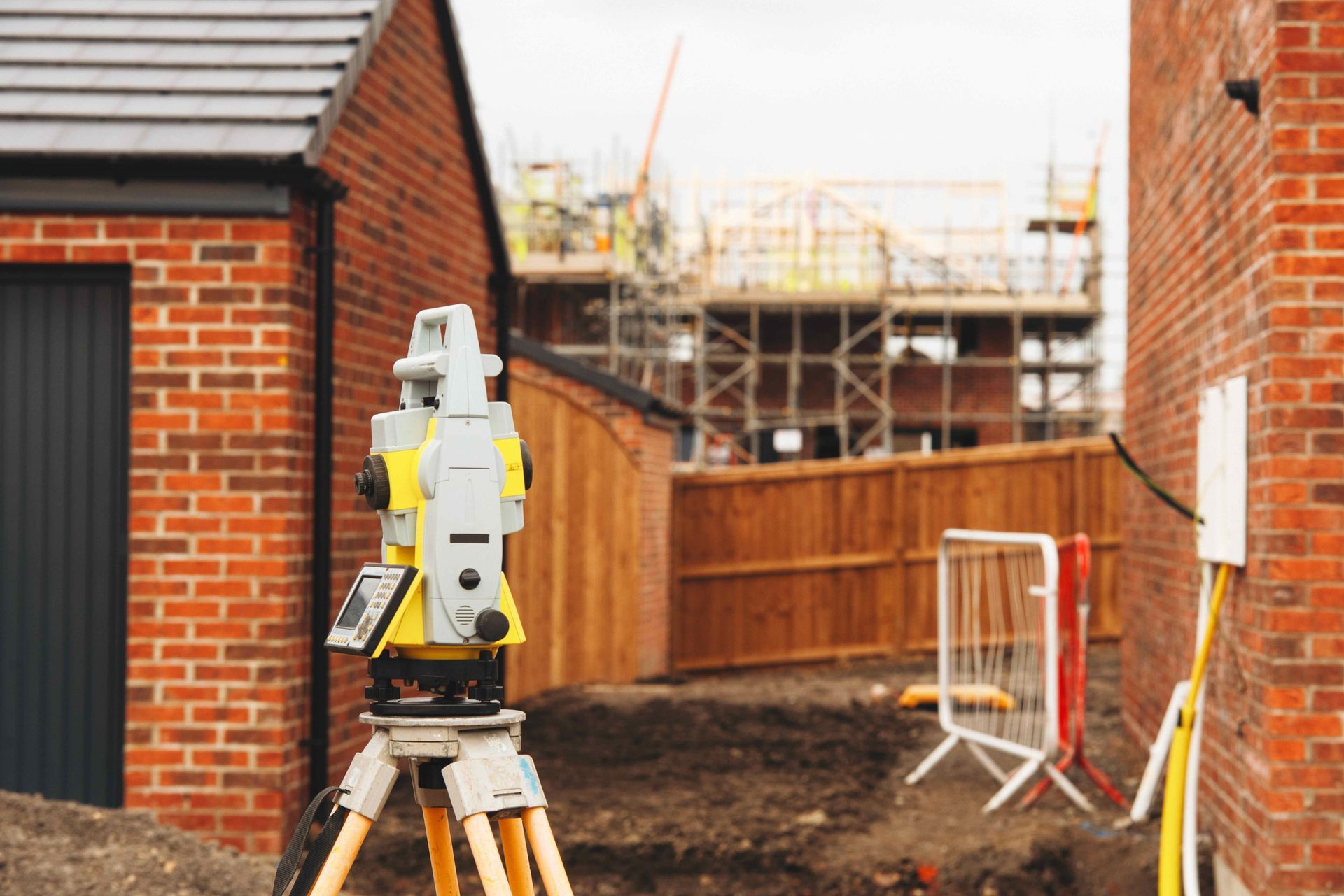 Surveying equipment on tripod at a construction site between brick buildings Surveying equipment on tripod at a construction site between brick buildings