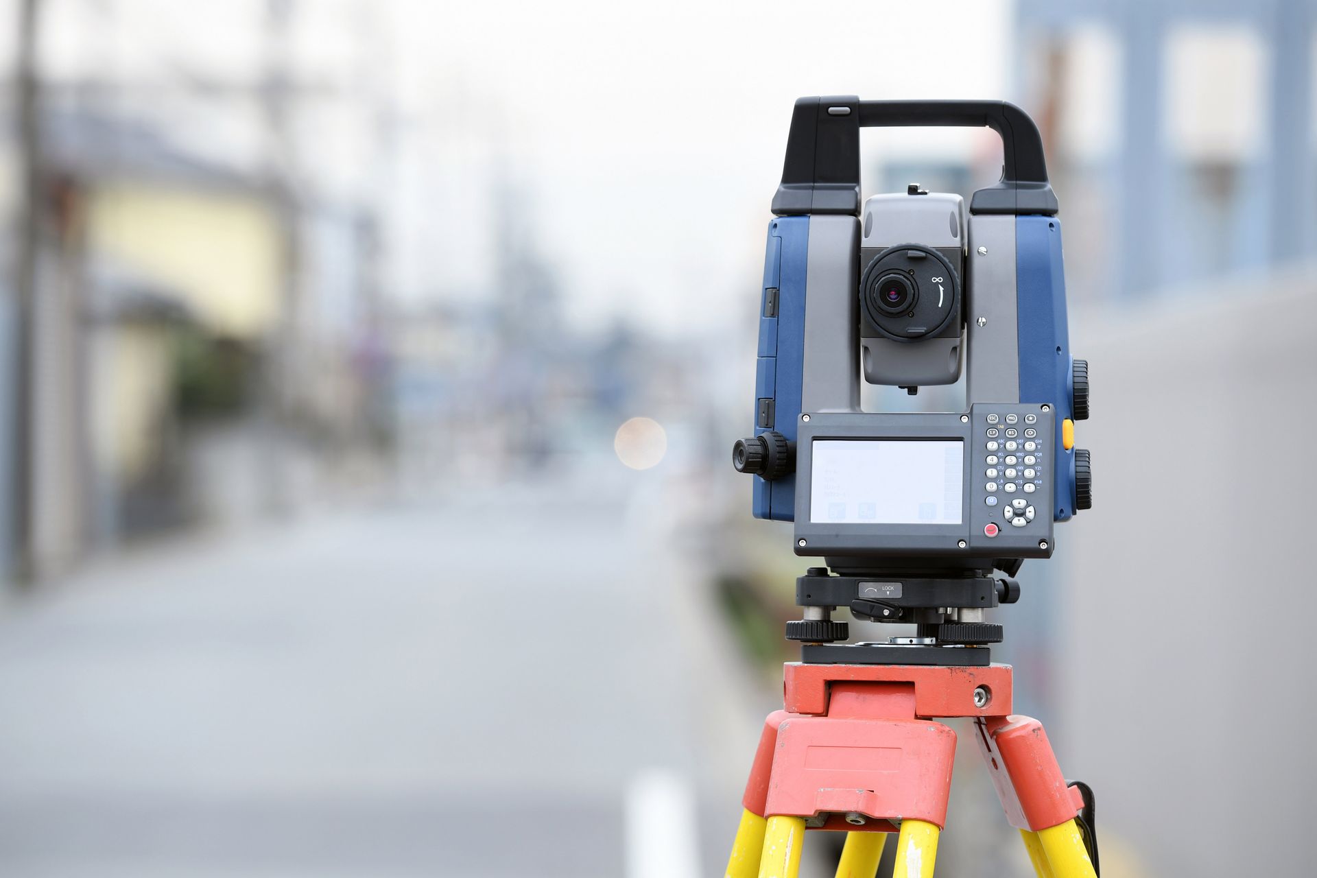 Surveying total station on a tripod outdoors, with blurred street background Surveying total station on a tripod outdoors, with blurred street background