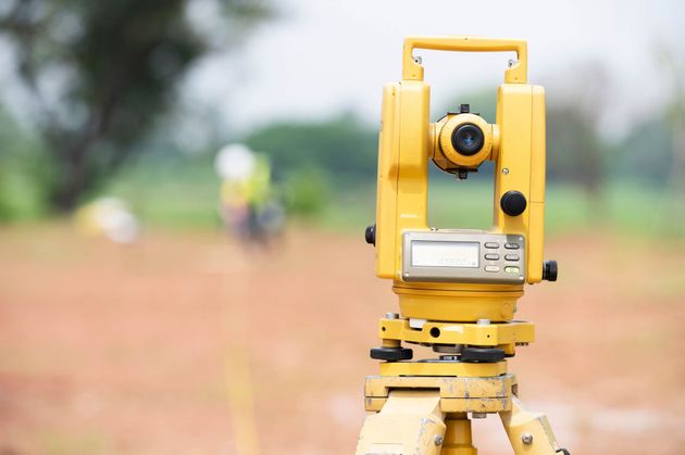 Yellow surveying instrument on tripod in a field with blurred background