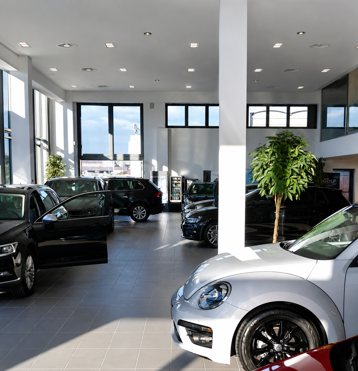 Un'auto rossa è parcheggiata in uno showroom accanto a un'auto argentata