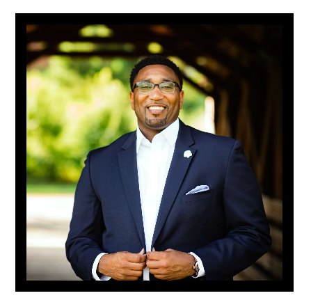 A man in a suit and tie is standing in front of a bridge.