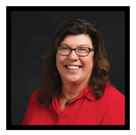 A woman wearing glasses and a red shirt is smiling for the camera.