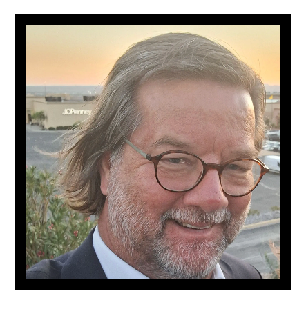 A man wearing glasses and a suit is smiling for the camera.