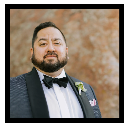 A man with a beard is wearing a tuxedo and bow tie.