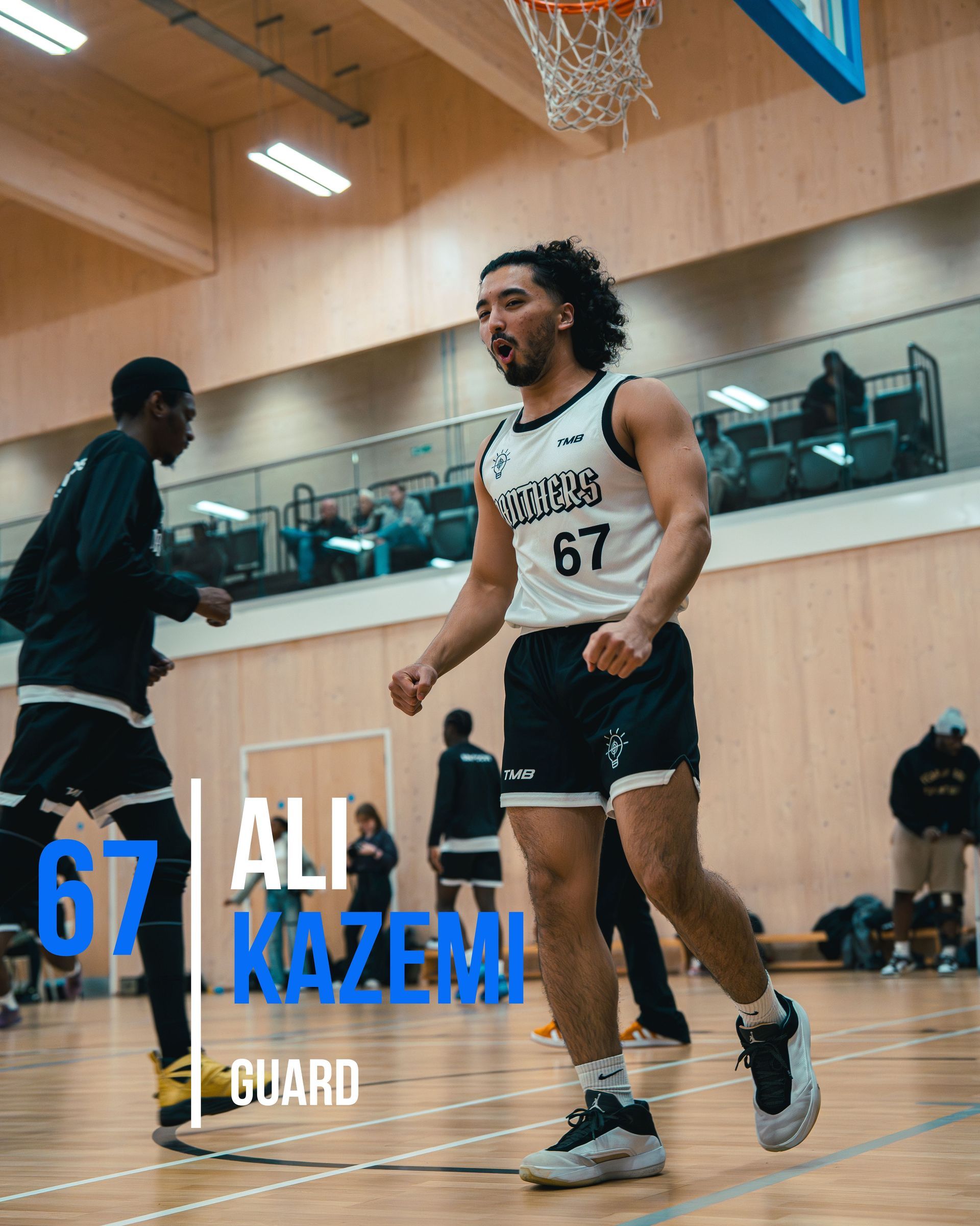 Basketball player Ali Kazemi wearing jersey 67, runs the court. Indoor gym setting.