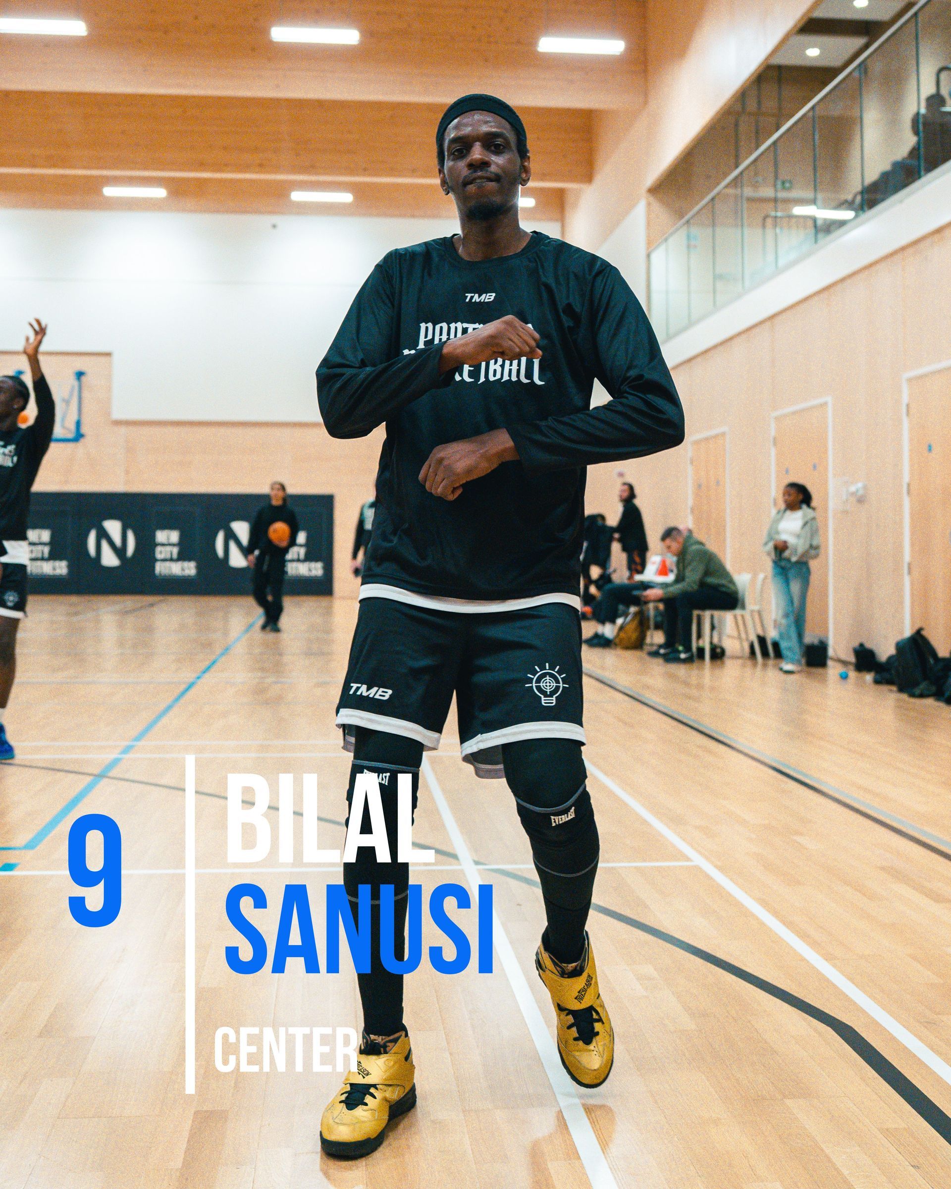 Basketball player Bilal Sanusi in a gym, wearing black uniform and gold shoes.