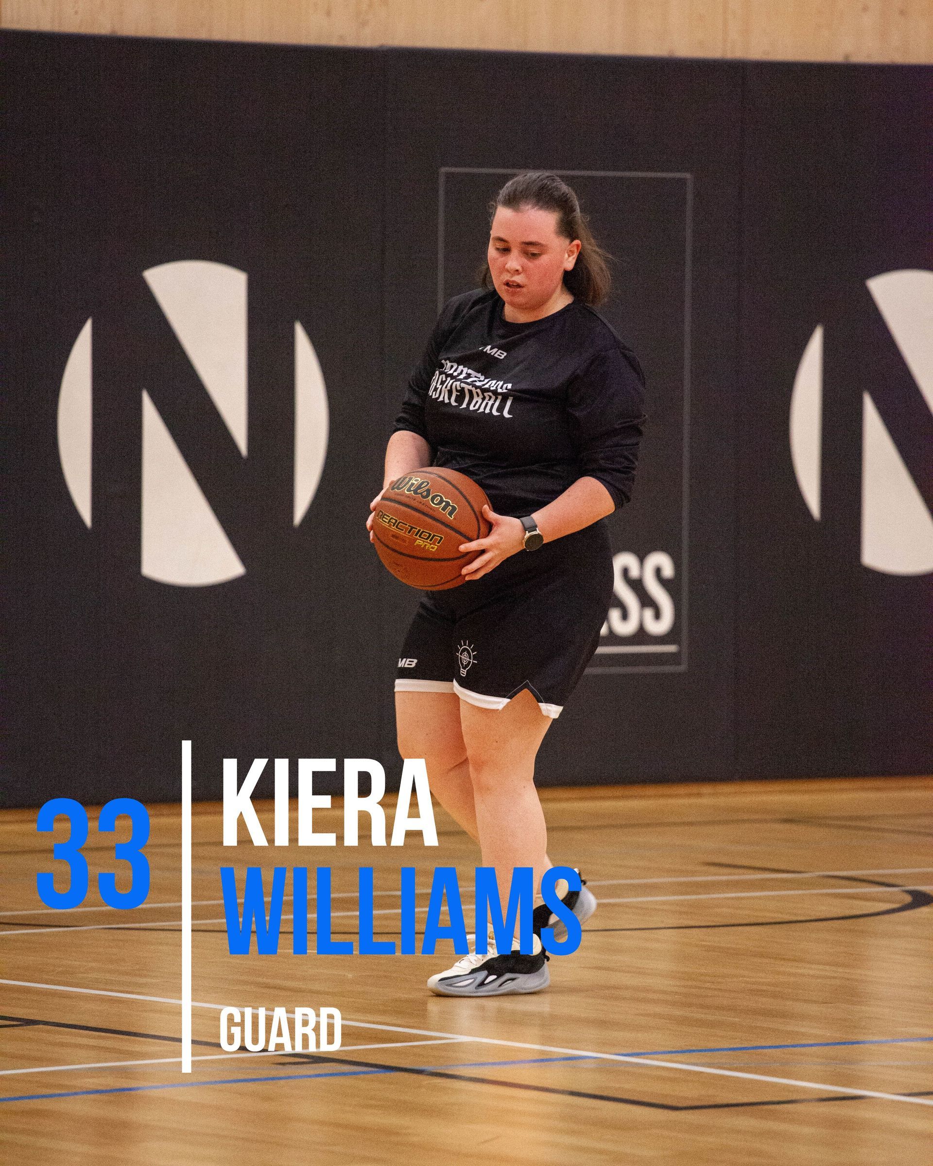 Basketball player Kiera Williams in a blue uniform, holding the ball, preparing to play on the court.