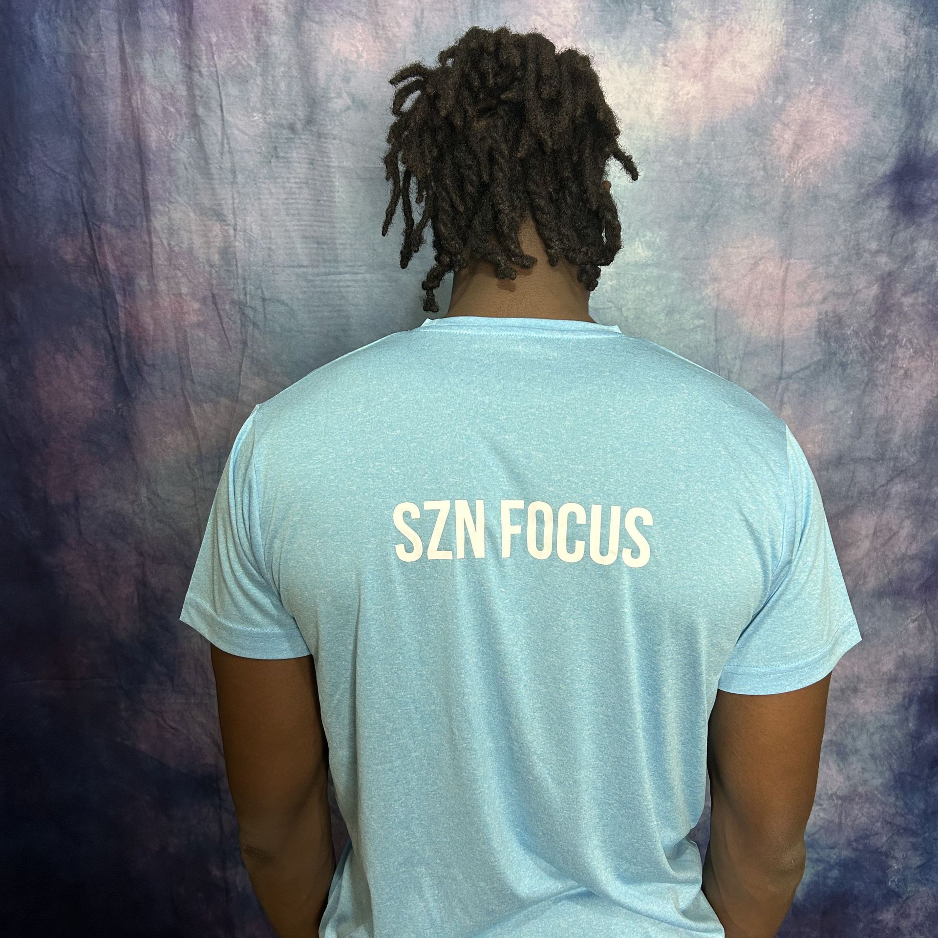 Man wearing a light blue t-shirt with a white lightbulb-shaped graphic that has a target inside.