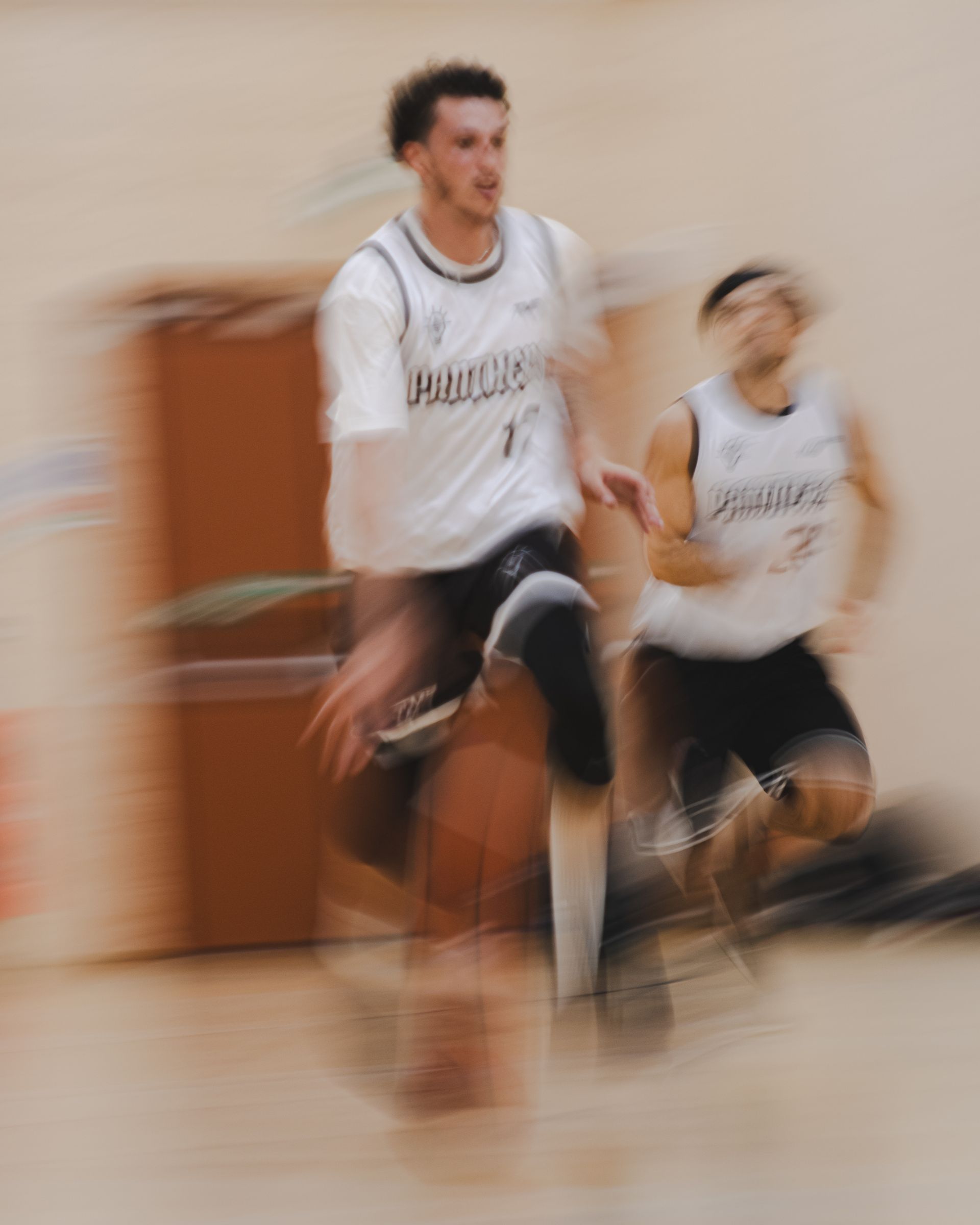 Basketball players in white jerseys running on a court, motion blur.