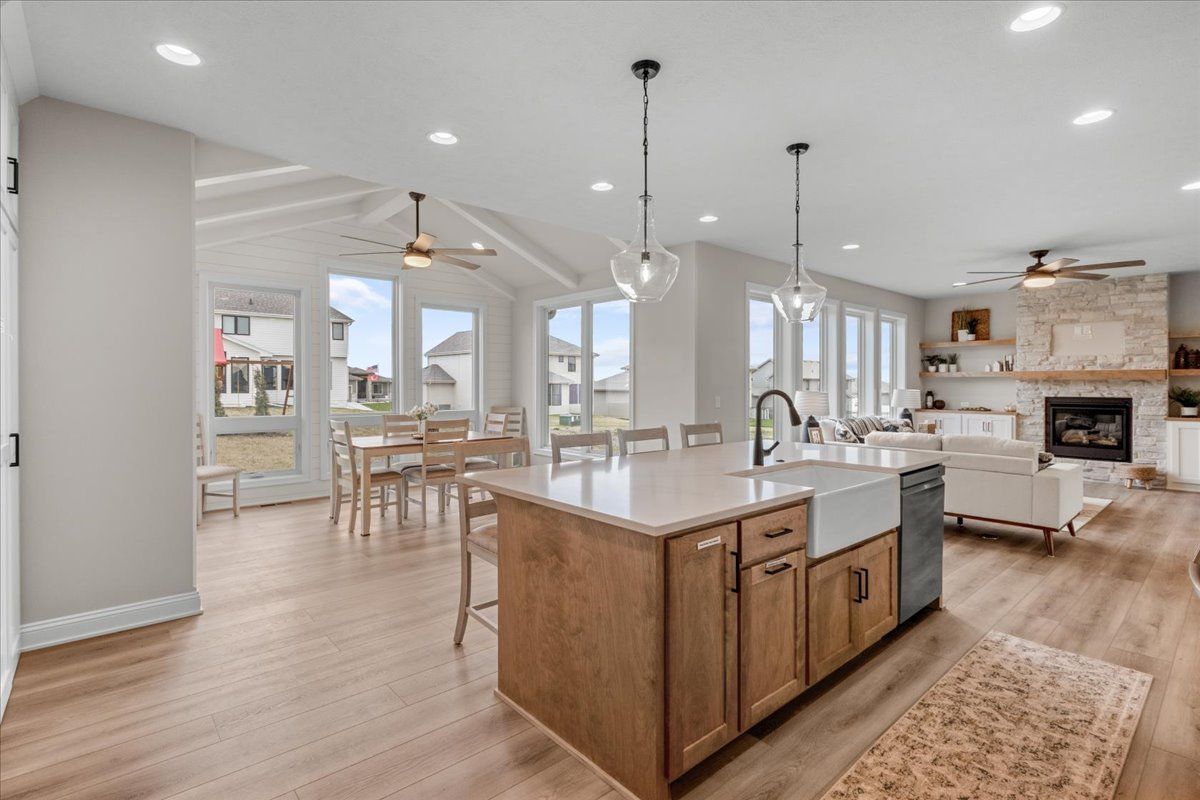 Bright open kitchen and dining area with island, white cabinets, wood floors, and large windows