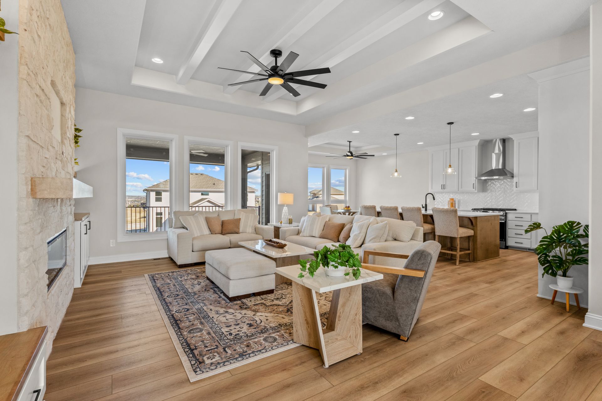 Bright open-concept living room with white walls, wood floors, large windows, and modern neutral мебели