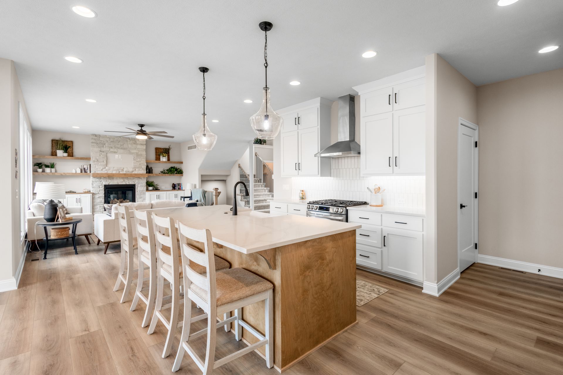 Bright modern kitchen with white cabinets, wood island, and barstools in an open floor plan