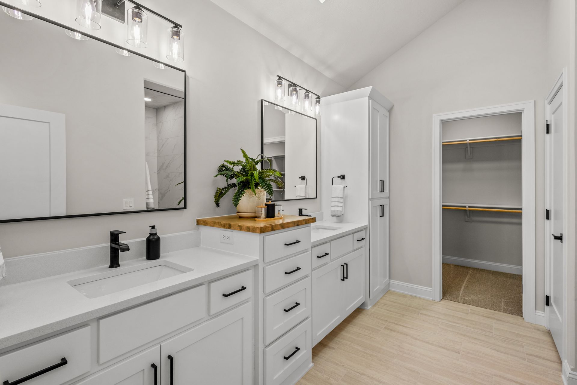 Bright modern double vanity bathroom with white cabinets, mirrors, and an open linen closet.