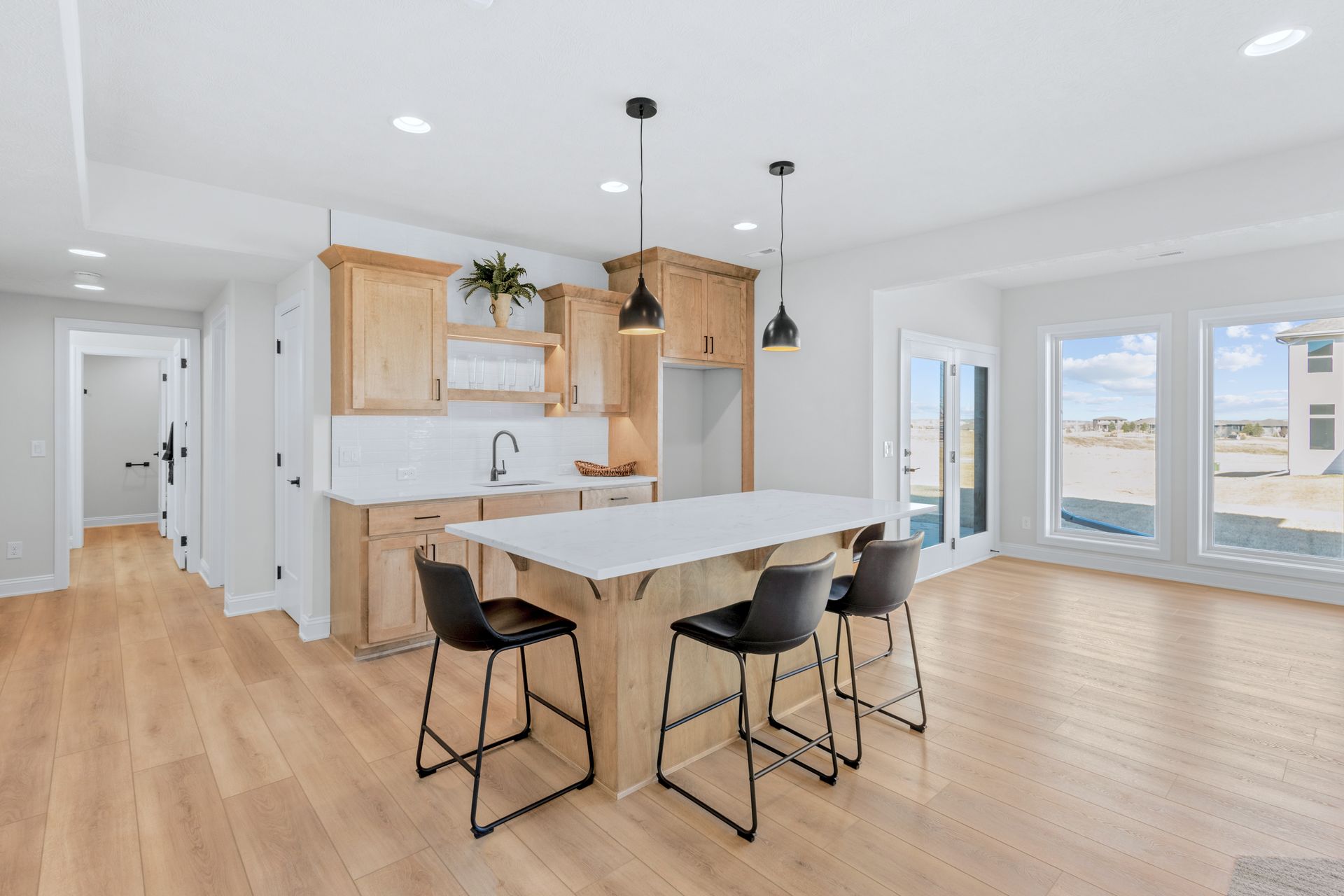 Bright open kitchen and dining area with light wood floors, white walls, and a table with four chairs.