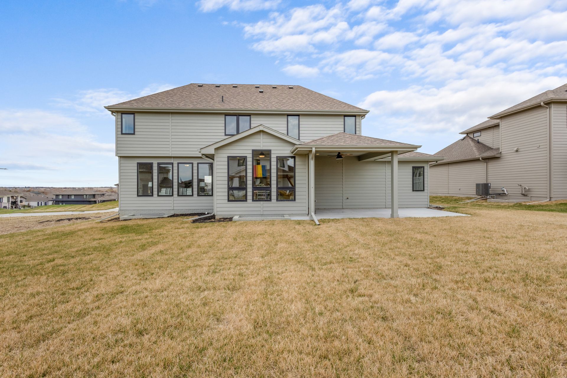 Two-story suburban house with attached garage and large front lawn under a cloudy sky