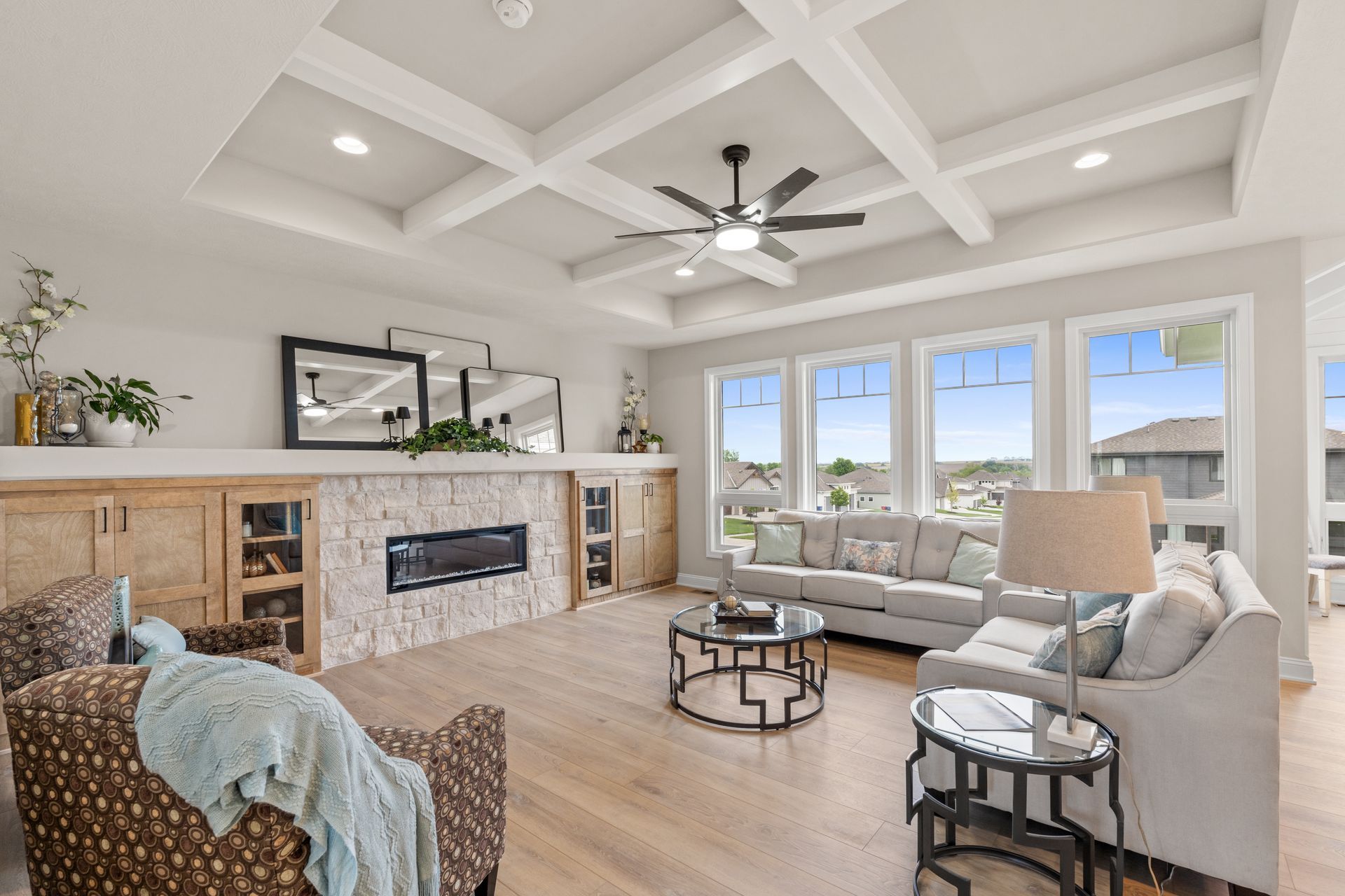 Bright living room with vaulted ceiling, stone fireplace, gray sofas, and large windows looking outside