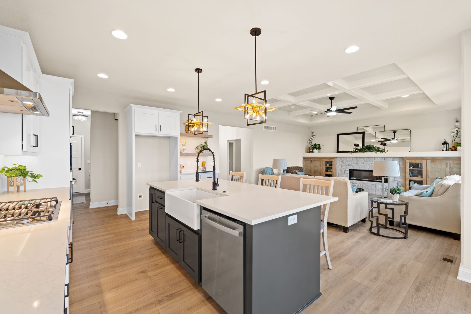 Bright open-plan kitchen and living room with white cabinets, gray island, and light wood floors