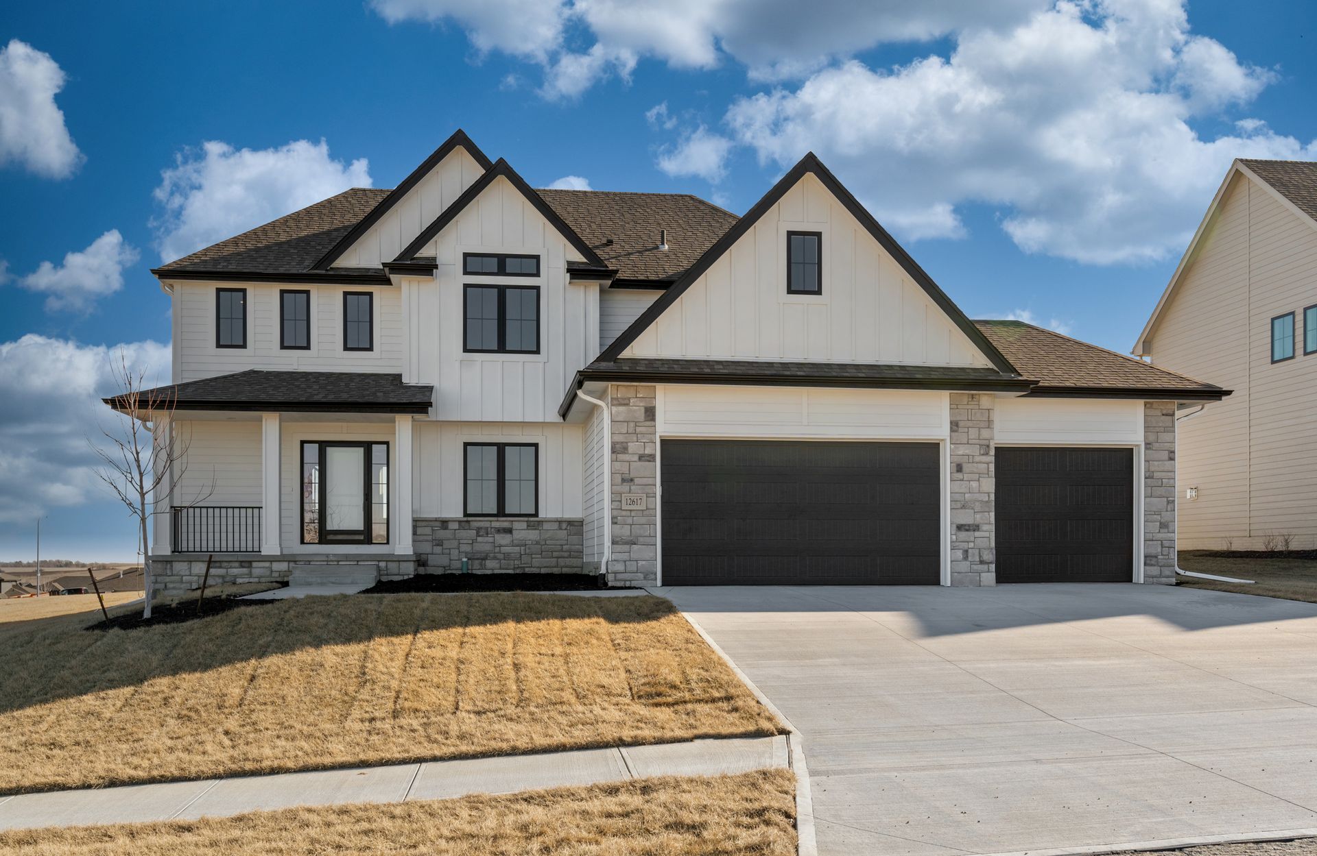 New suburban two-story house with a three-car garage under a blue sky