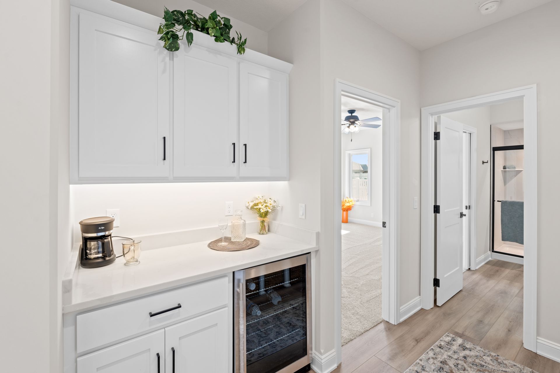 Bright white hallway with built-in cabinets, countertop, and a doorway to a bedroom or closet.