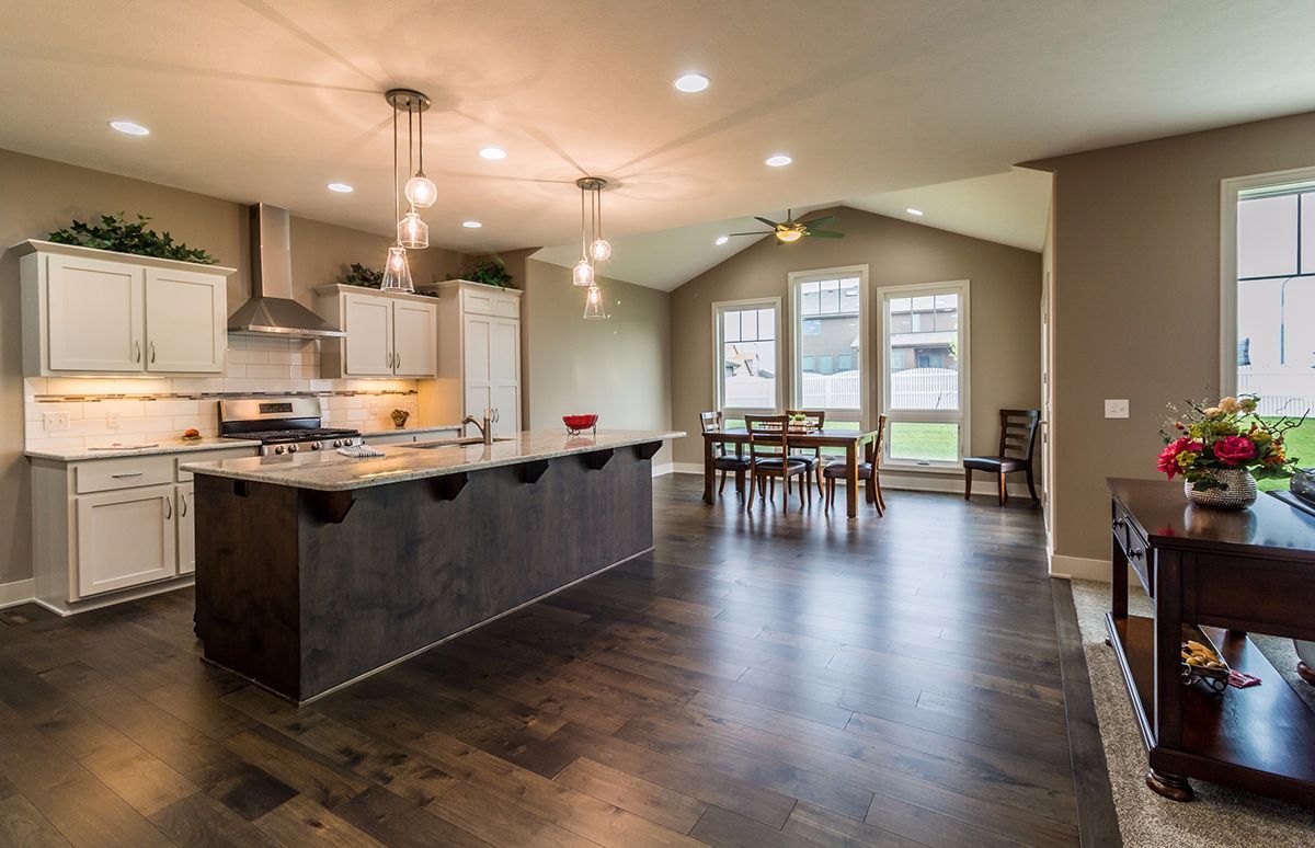 Modern kitchen and dining area with dark island, white cabinets, and large windows