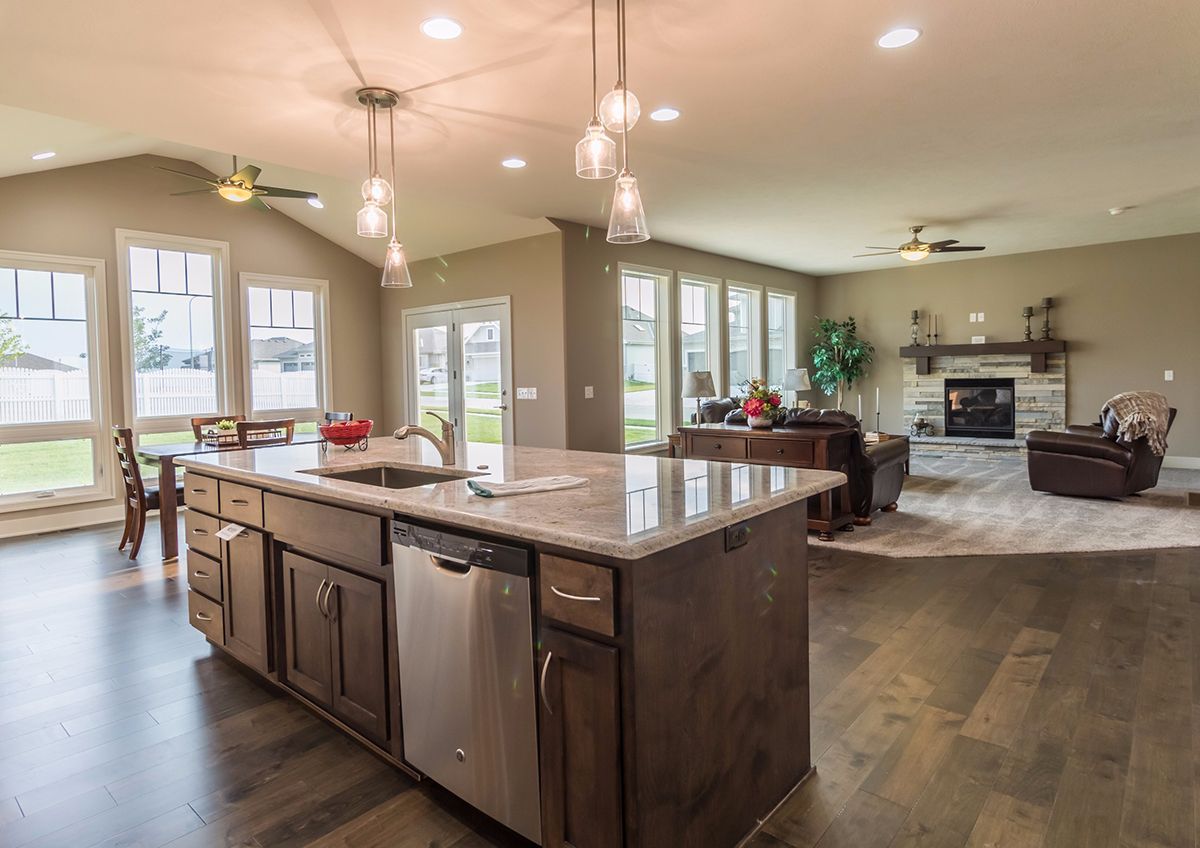 Spacious modern kitchen and living area with island, hardwood floors, fireplace, and large windows