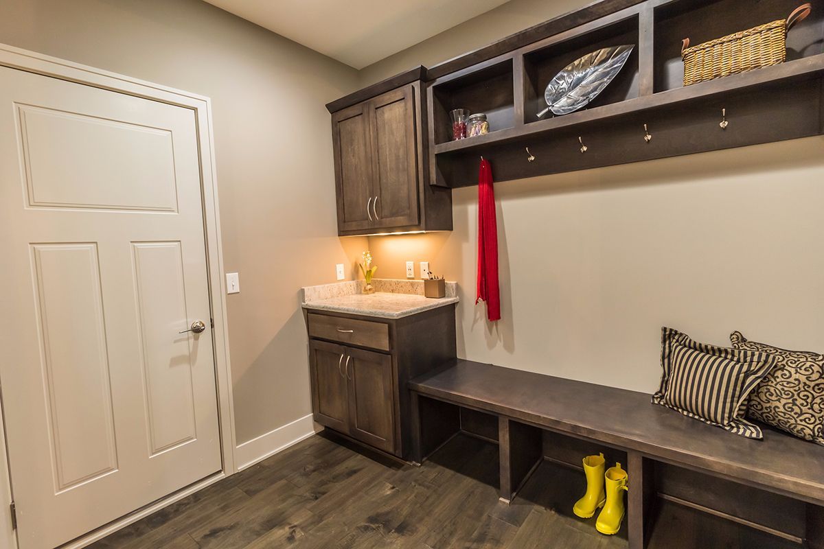 Built-in mudroom bench with cubbies, sink, and hooks in a beige entryway.