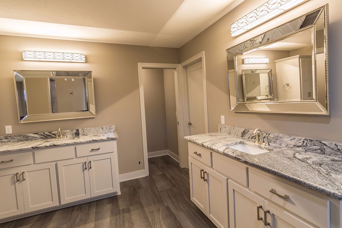 Bright modern bathroom with double vanity, large mirrors, and beige walls and cabinets.