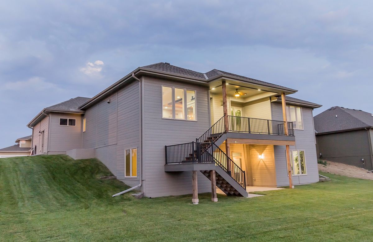 Two-story suburban house at dusk with lit windows, a front staircase, and a grassy yard.