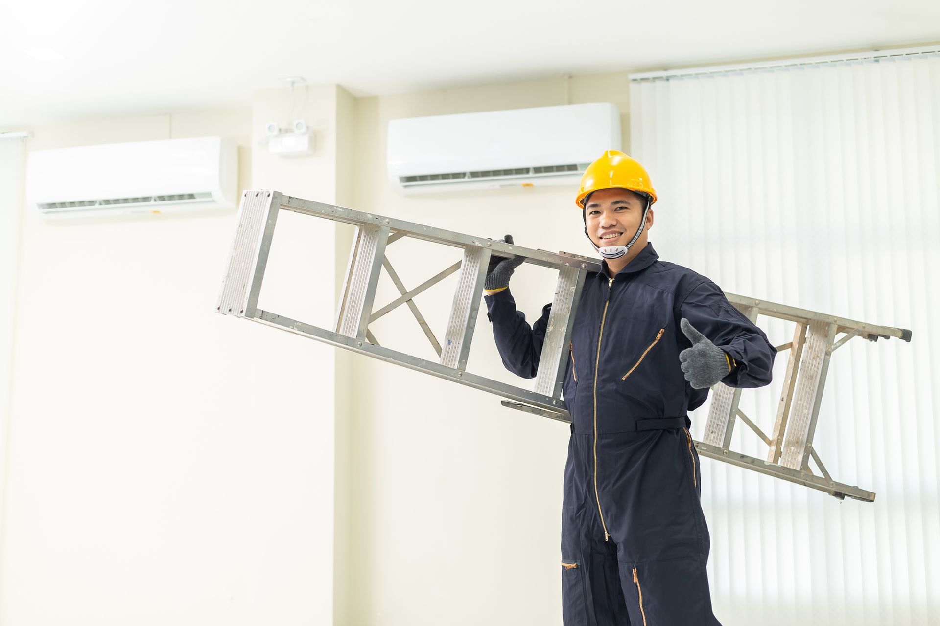 An Air Conditioning Installation Contractor carries a ladder inside an office space.