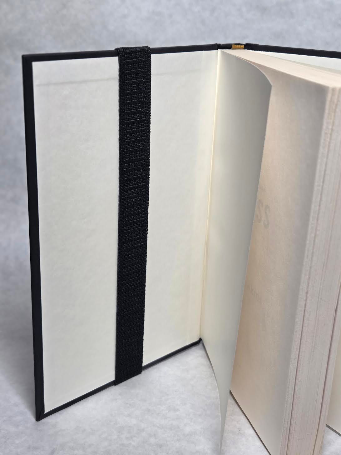 Decorative notebook cover with a burgundy spine, cream front, and patterned pocket holding a pen.
