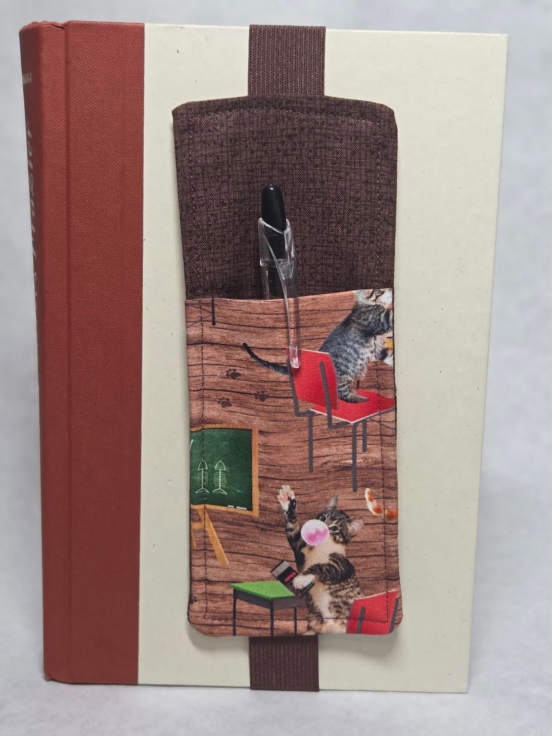 Decorated handmade journal with red spine, cream cover, and fabric collage band on the front.
