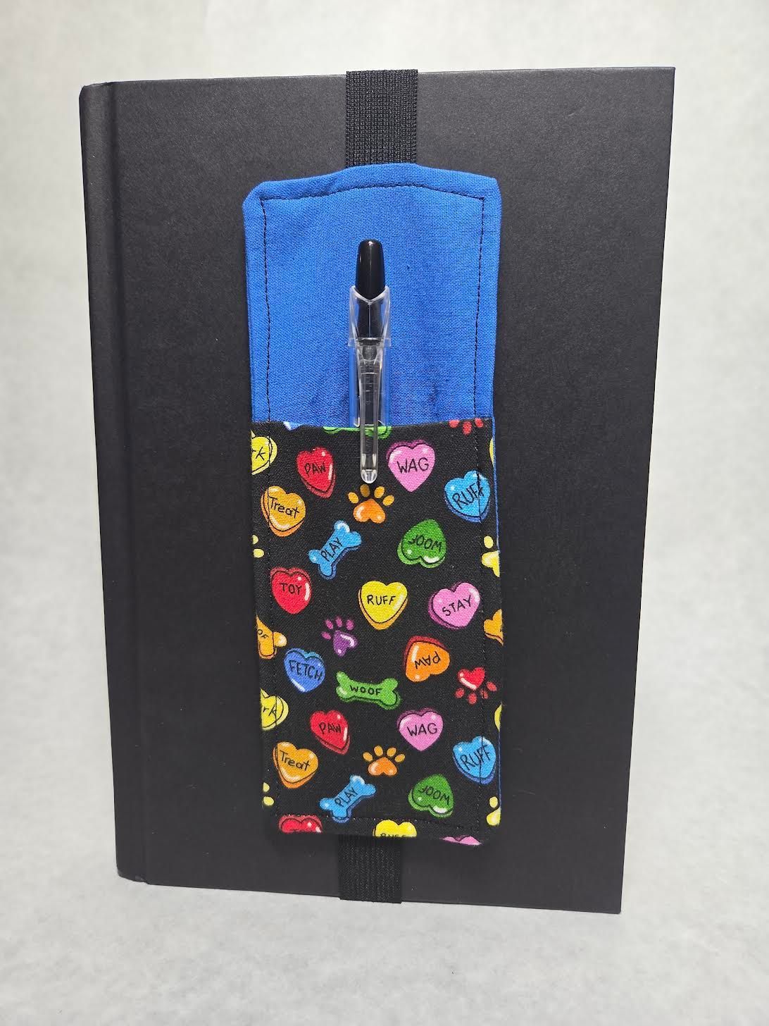 Black notebook with a blue and heart-patterned zipper pencil case centered on it