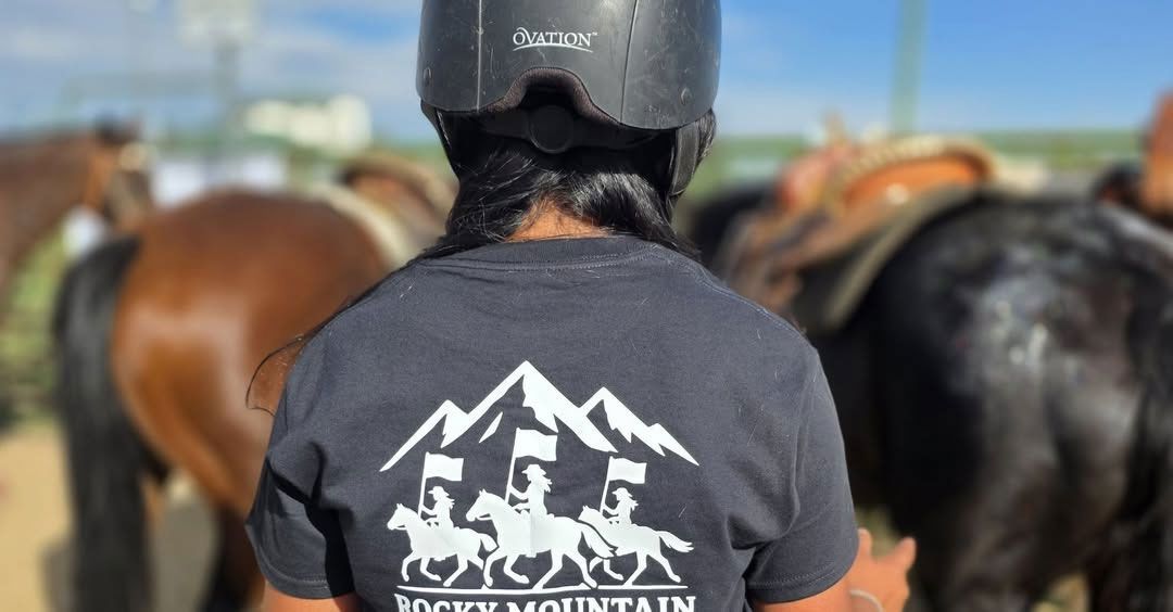 A group of riders on horseback holding American flags during a sunny, outdoor equestrian event.