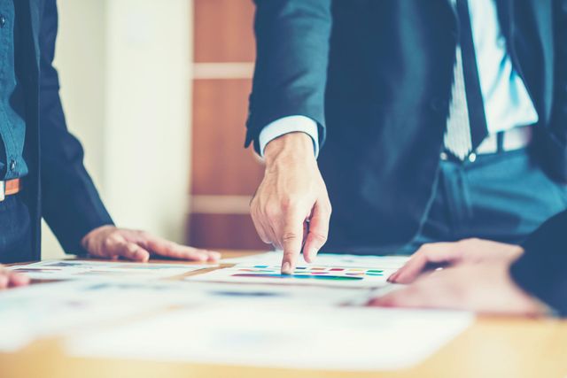 Businesspeople pointing at charts on a desk during a meeting