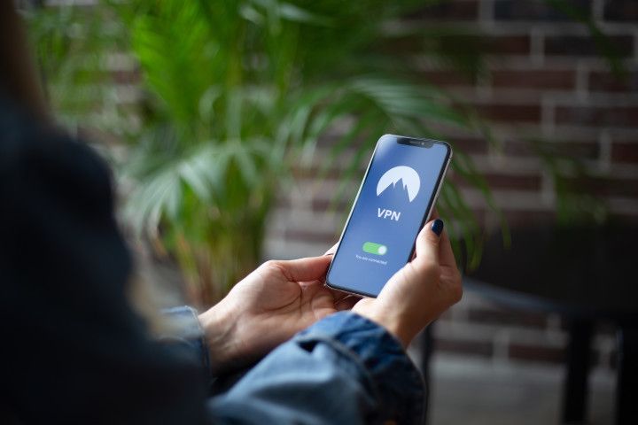 Hands holding a smartphone with a VPN app open in a blurred outdoor setting.