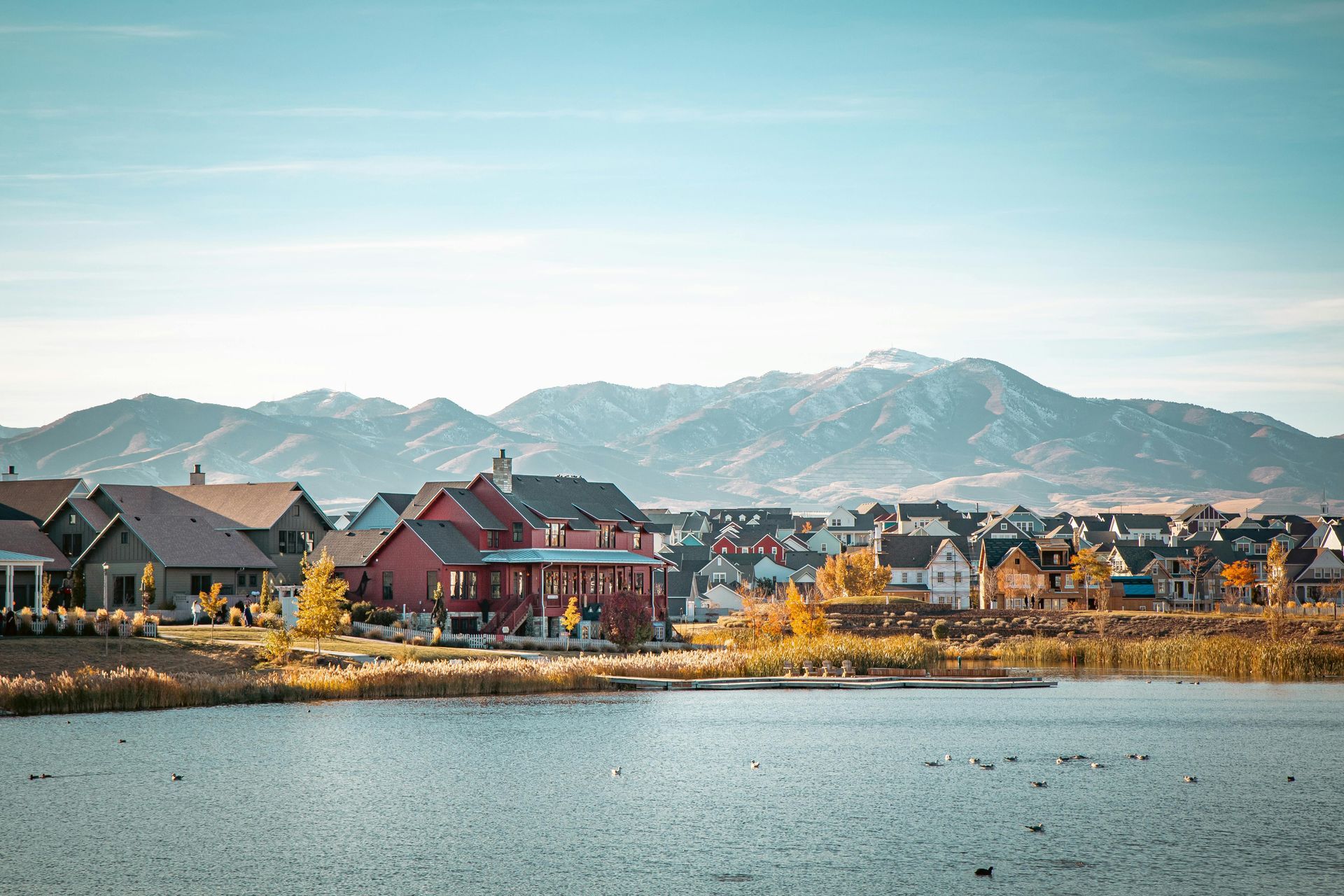 A row of houses next to a lake with mountains in the background.