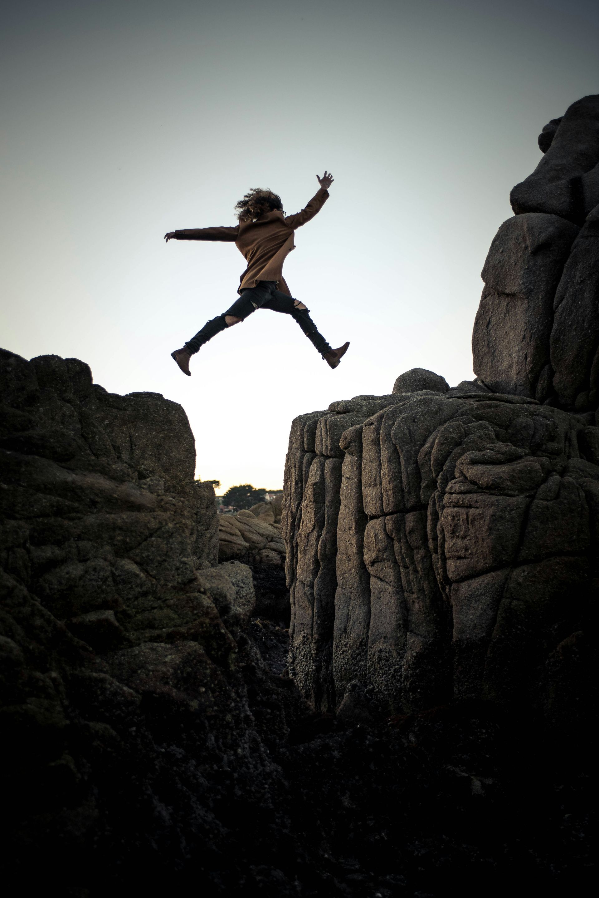 A person is jumping over a rocky cliff