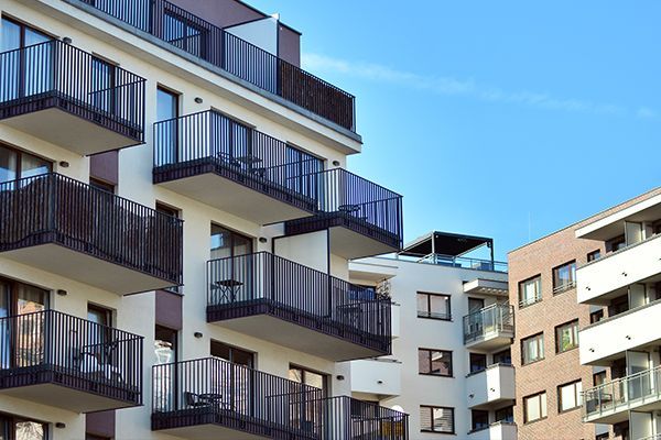 Modern apartment buildings with balconies against a clear blue sky.