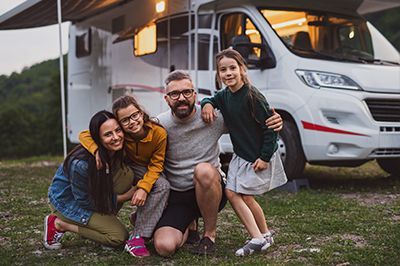 Tan and black RV parked in front of a house.
