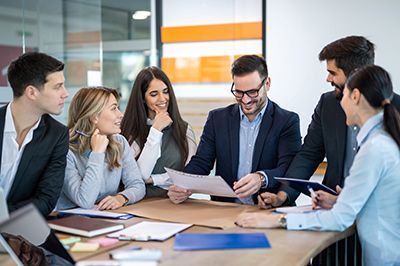 Team of coworkers in a meeting, reviewing documents around a conference table in a modern office.