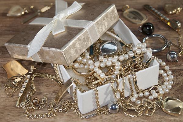 Open jewelry boxes filled with pearls, gold chains, and rings on a wooden surface