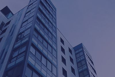 Low-angle shot of a tall, modern building with many windows against a blue sky.