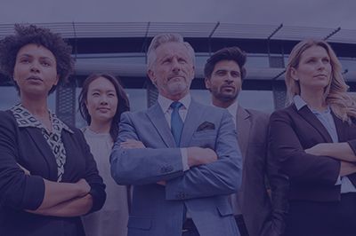 Business team, arms crossed, standing in front of a modern building.