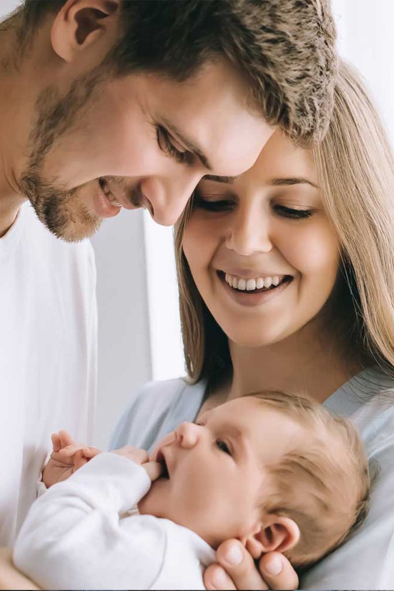 Parents smiling at a baby they are holding.