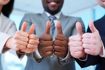 Three people in business suits give thumbs up.