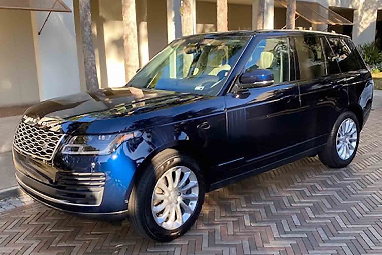 Dark blue luxury SUV parked outside a building on a patterned driveway