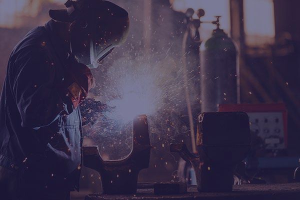 Welder in protective mask, sparks flying in a workshop.