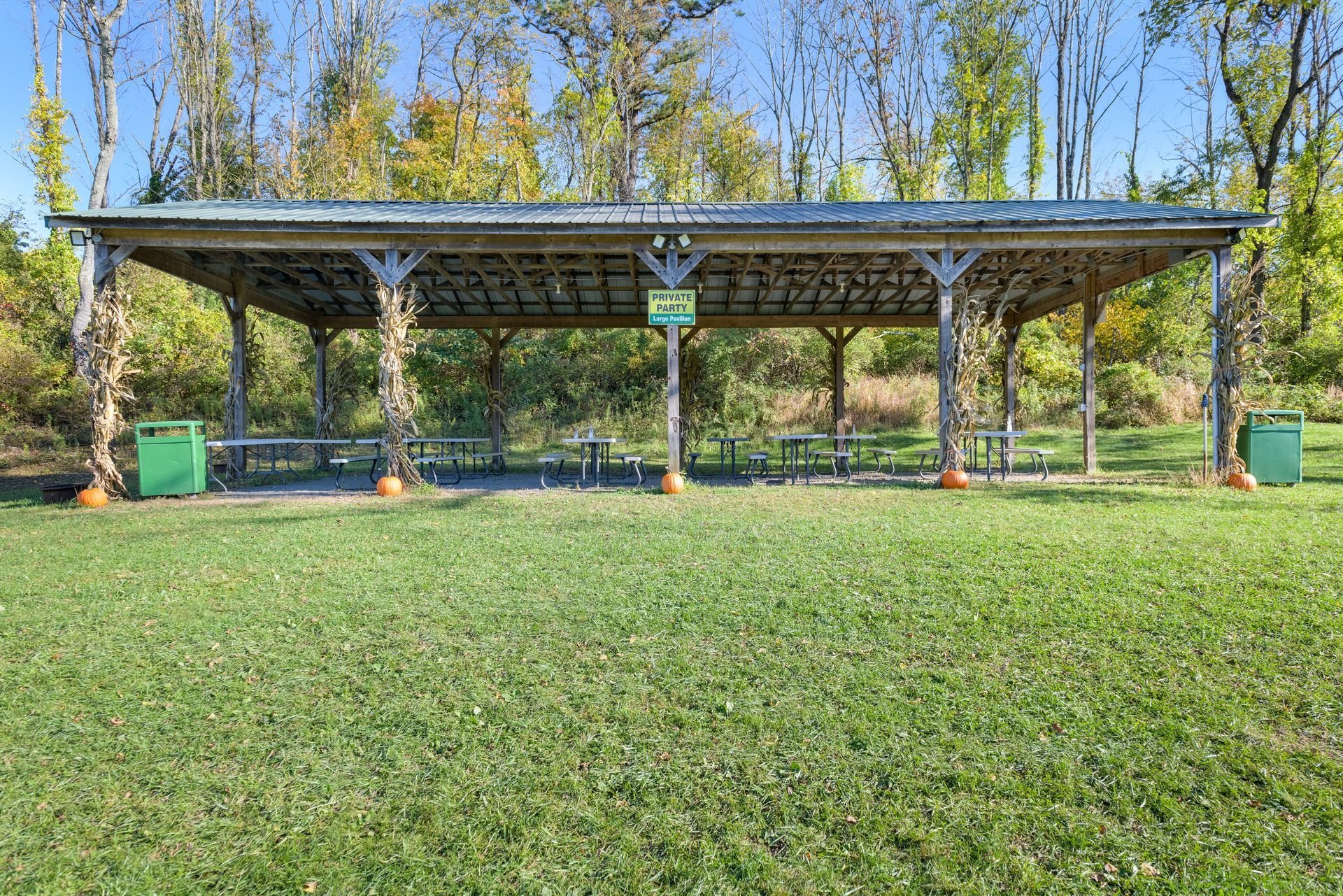 There is a picnic shelter in the middle of a grassy field.