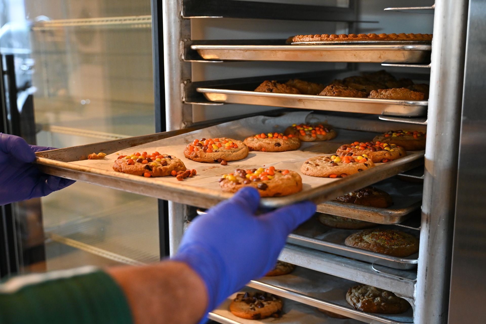 A person is taking a tray of cookies out of an oven.