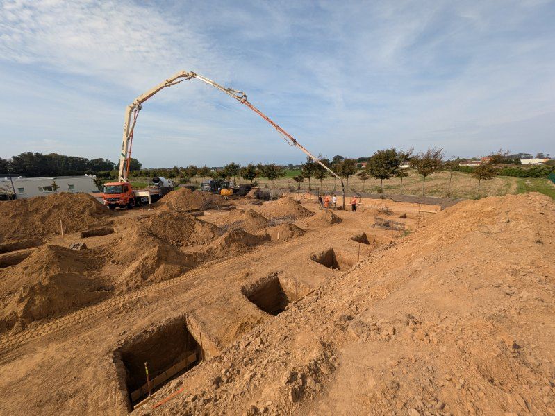 Pompe à béton à flèche au-dessus des fouilles d'un bâtiment industriel au Havre
